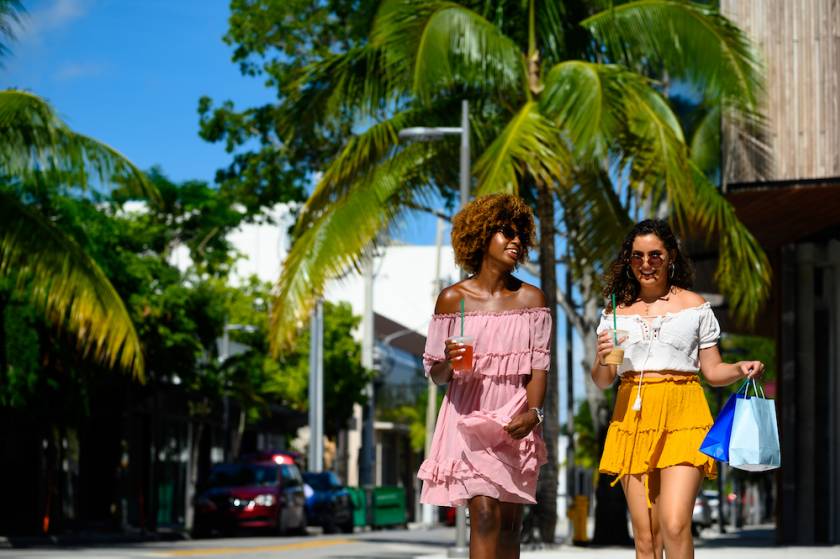 two women walking outside in a shopping area at the beach